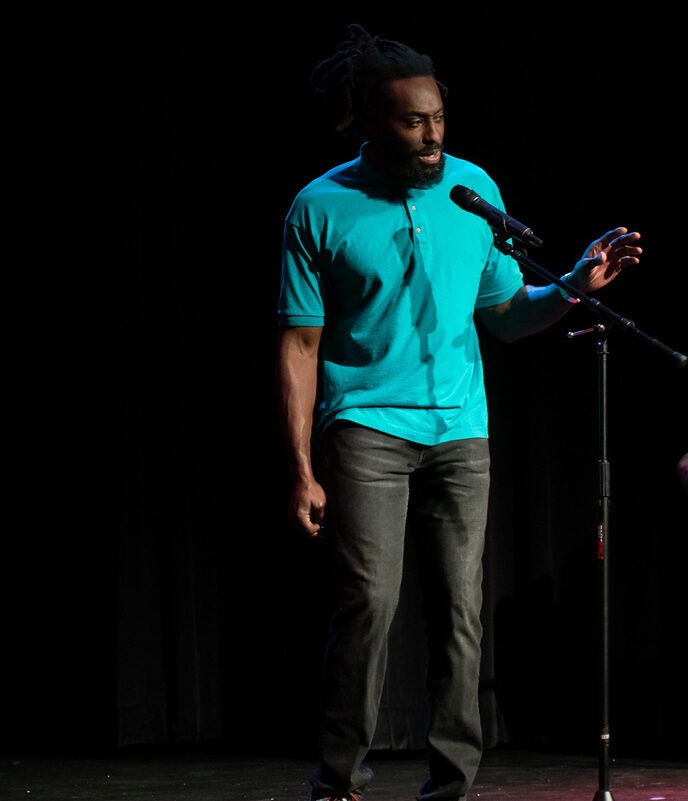 Casey Muze speaking at a microphone on stage.